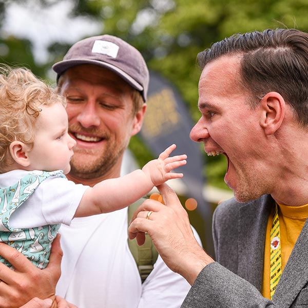 An image of a family carrying a baby and smiling.