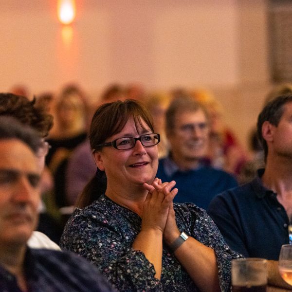 A shot of the crowd at HIF featuring a woman clasping her hands together looking onwards in amazement.