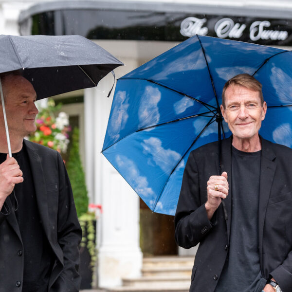Two men stood underneath umbrellas.