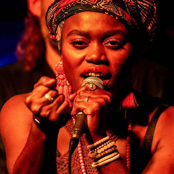 A performer singing on stage with a serious expression.