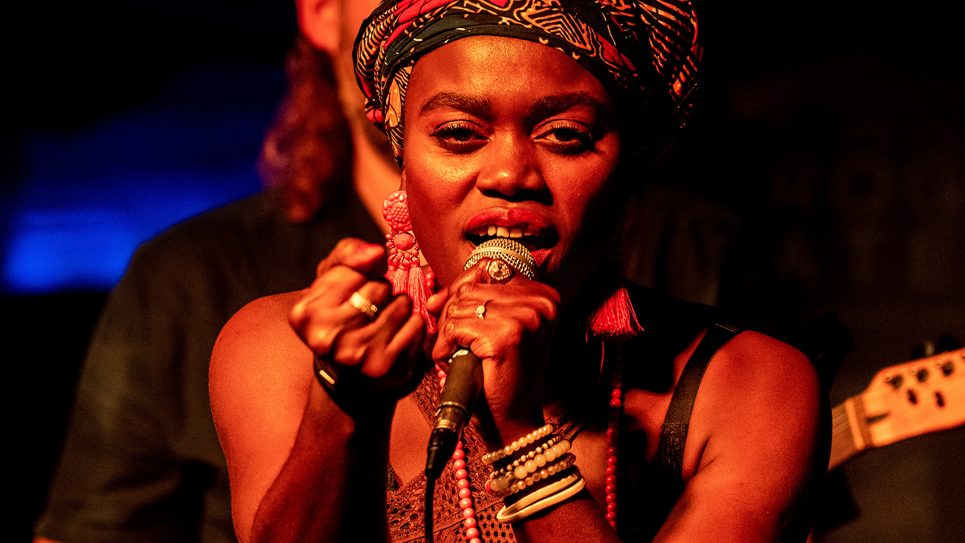 A performer singing on stage with a serious expression.