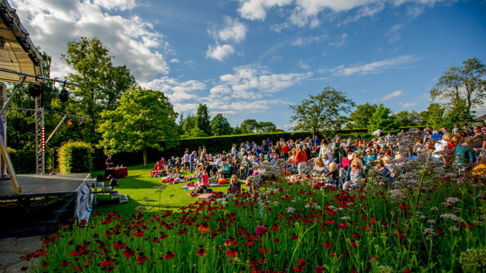 The audience watching an Oddsocks performance in the RHS Harlow Carr gardens. It's a beautiful summer evening.