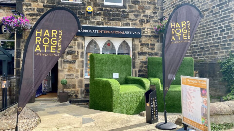 Outside the box office there are two armchairs made of artificial grass. There are signs signposting the festival.