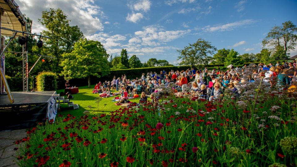 The audience watching an Oddsocks performance in the RHS Harlow Carr gardens. It's a beautiful summer evening.